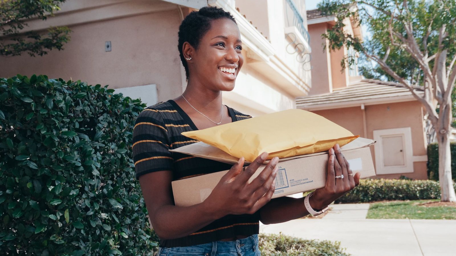 Une femme sourit en tenant les colis qu'elle vient de recevoir.